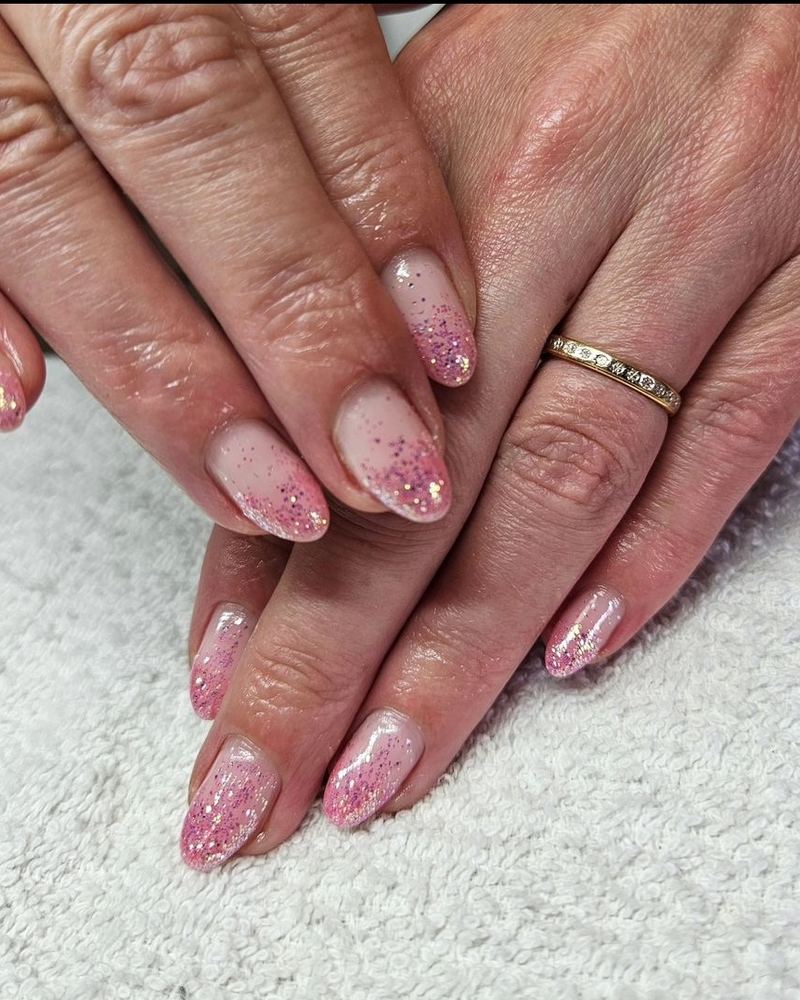 Ongles rose pâle pailletés sur une serviette blanche.